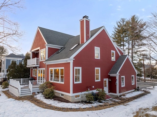 exterior space with roof with shingles, a chimney, and a balcony