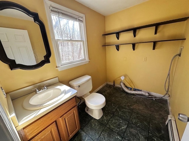 half bath with baseboard heating, vanity, and toilet