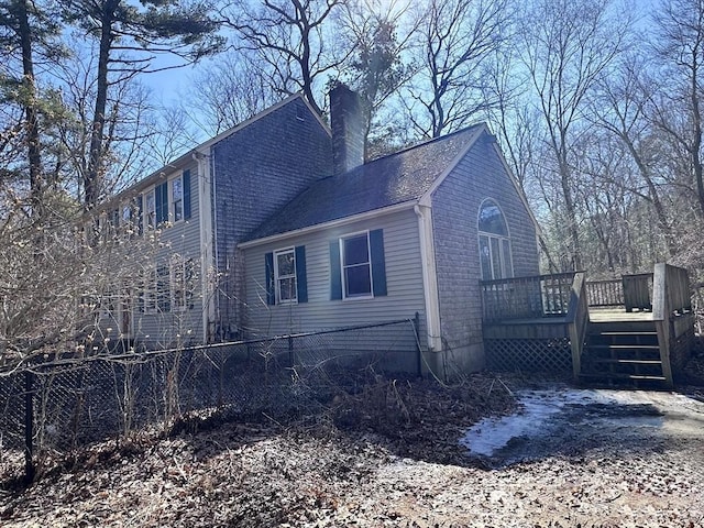 view of side of home with a deck and a chimney