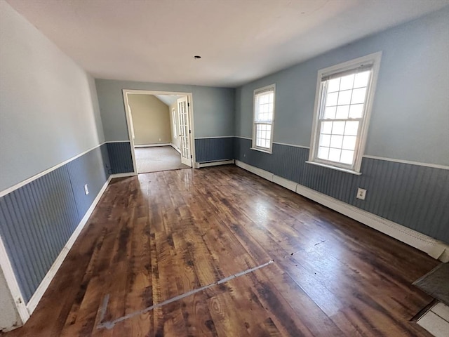 unfurnished room with baseboard heating, hardwood / wood-style floors, and wainscoting