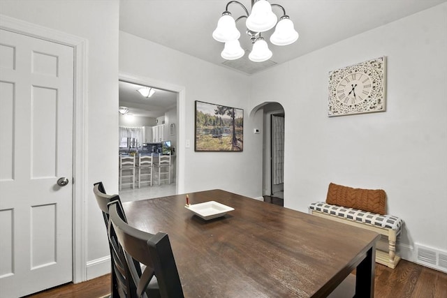 dining room with dark wood-type flooring and a notable chandelier