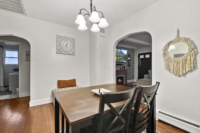 dining room with baseboard heating, an inviting chandelier, and dark wood-type flooring