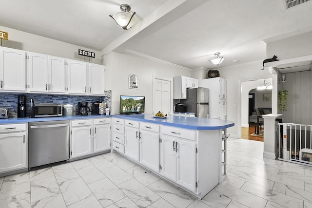 kitchen with crown molding, appliances with stainless steel finishes, white cabinets, decorative backsplash, and kitchen peninsula