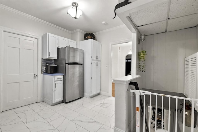 kitchen with stainless steel refrigerator, crown molding, and white cabinets