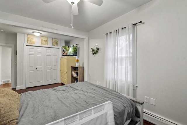 bedroom featuring dark hardwood / wood-style flooring, a baseboard heating unit, ceiling fan, and a closet