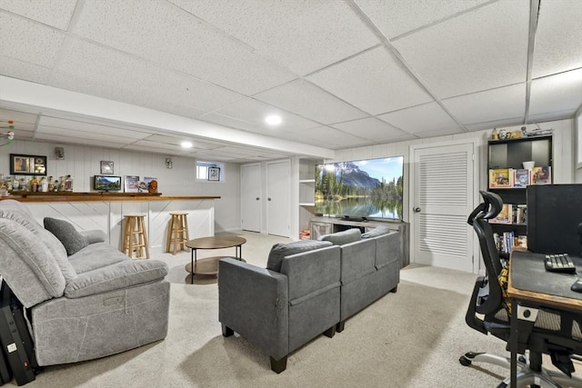 carpeted living room featuring a paneled ceiling and bar area