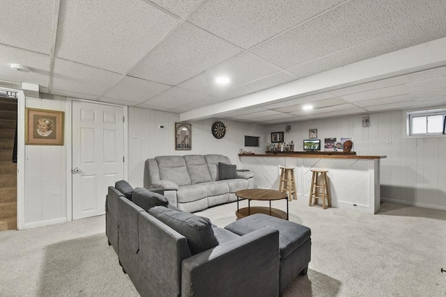 carpeted living room with a paneled ceiling and bar area