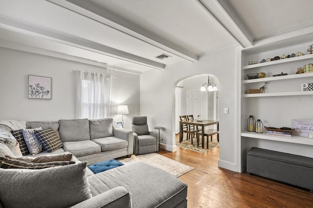 living room with a notable chandelier, beam ceiling, and hardwood / wood-style flooring