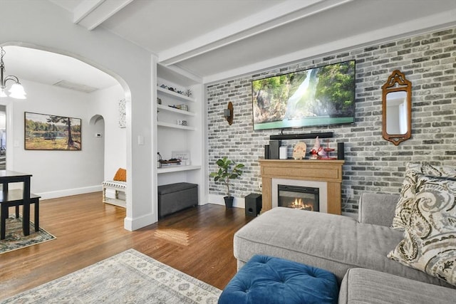 living room featuring beamed ceiling, brick wall, hardwood / wood-style floors, and built in features