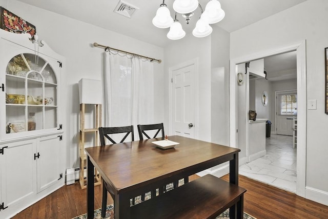 dining space with a baseboard heating unit, dark wood-type flooring, and an inviting chandelier