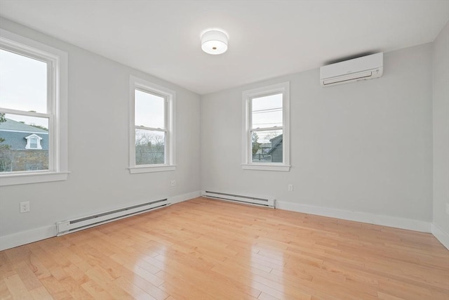 empty room featuring a wall unit AC, a baseboard radiator, and light hardwood / wood-style floors