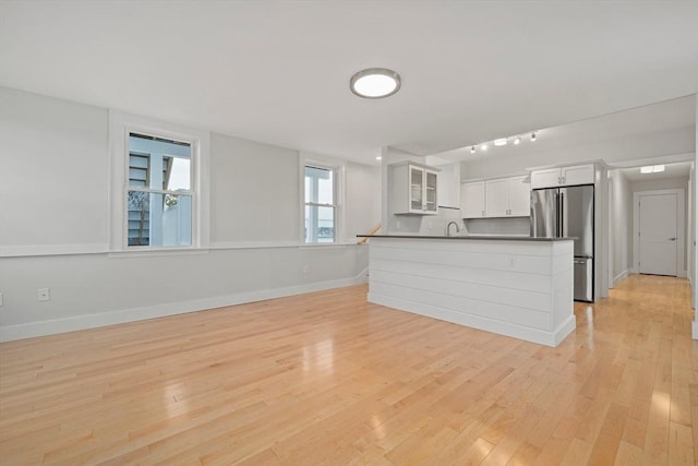 kitchen featuring white cabinets, stainless steel fridge, light hardwood / wood-style floors, and sink