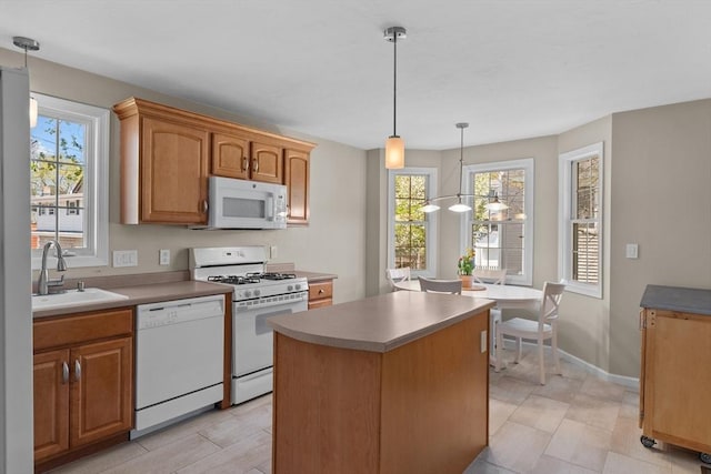 kitchen with white appliances, plenty of natural light, a sink, and a center island