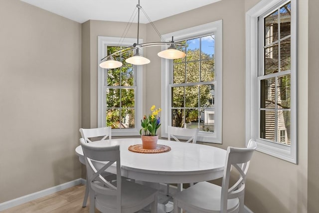 dining area featuring baseboards, an inviting chandelier, and light wood finished floors