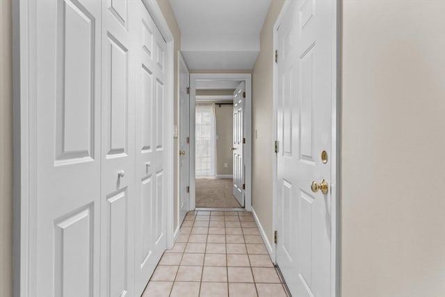 corridor featuring baseboards and light tile patterned floors