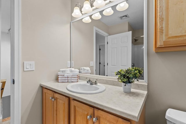 bathroom featuring visible vents, toilet, and vanity