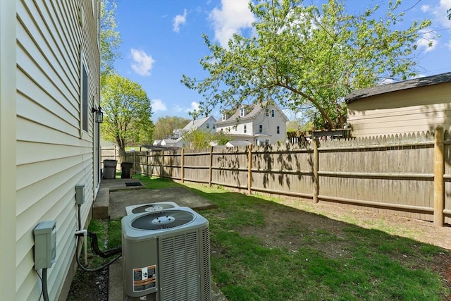 view of yard with a fenced backyard, central AC, and a residential view