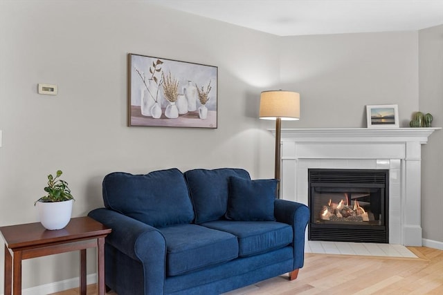 living room featuring baseboards, a tiled fireplace, and wood finished floors