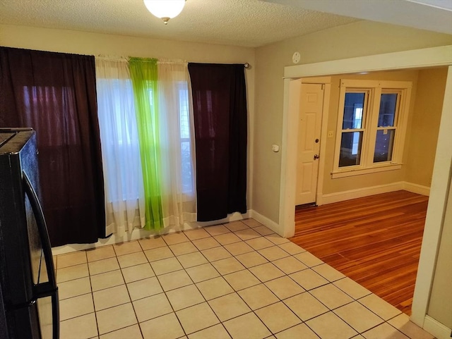 foyer entrance with a textured ceiling, a wealth of natural light, and light tile patterned flooring