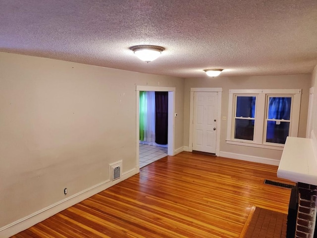 empty room featuring a textured ceiling and light hardwood / wood-style flooring