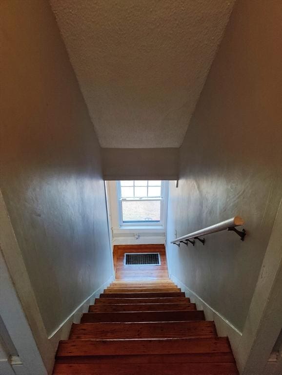 stairway featuring a textured ceiling