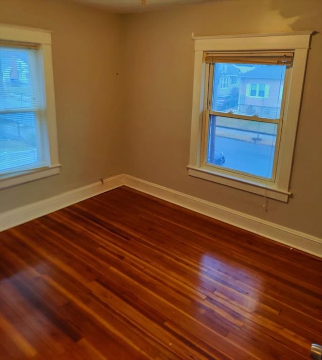 empty room with plenty of natural light and dark hardwood / wood-style flooring