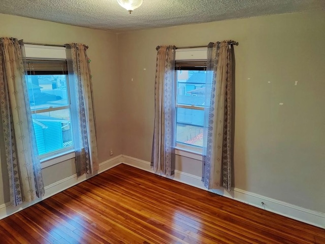 empty room with a wealth of natural light, hardwood / wood-style floors, and a textured ceiling