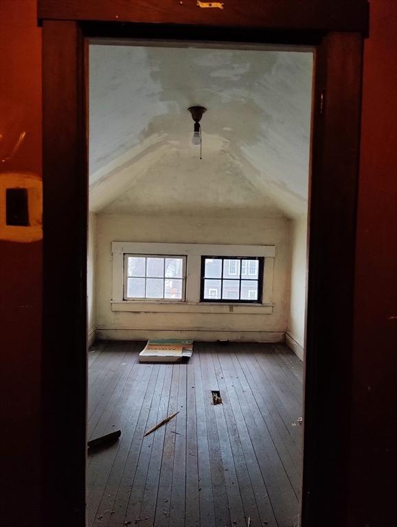 additional living space with hardwood / wood-style floors and lofted ceiling