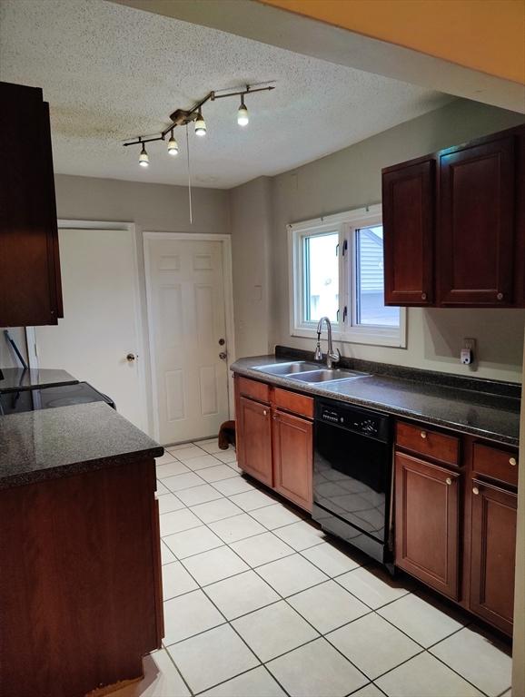 kitchen with dishwasher, a textured ceiling, light tile patterned flooring, and sink