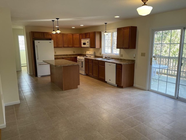 kitchen with a kitchen island, sink, white appliances, and hanging light fixtures