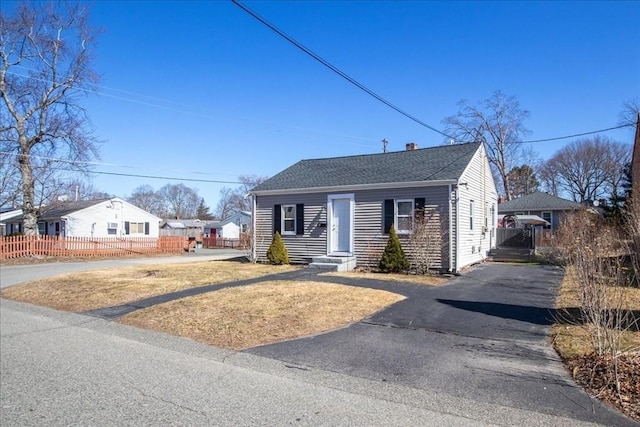 view of front facade with roof with shingles, driveway, and fence