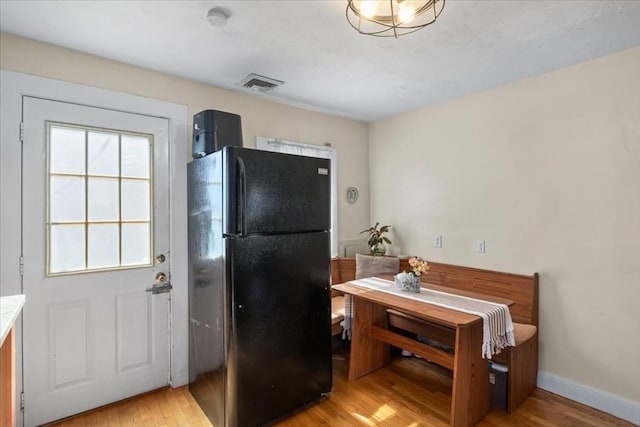 kitchen with visible vents, light wood-type flooring, freestanding refrigerator, and baseboards