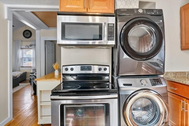 washroom with stacked washer and dryer, light wood-style flooring, and laundry area