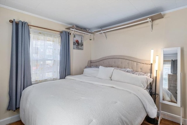 bedroom featuring crown molding, multiple windows, wood finished floors, and baseboards