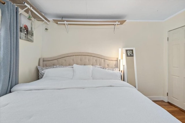 bedroom featuring baseboards, wood finished floors, and ornamental molding