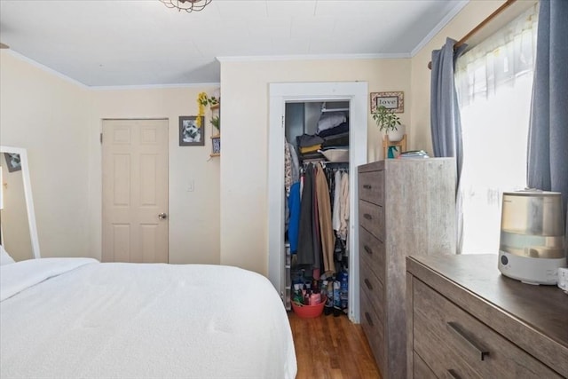 bedroom with a walk in closet, crown molding, wood finished floors, and a closet