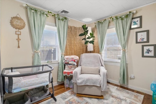 living area featuring visible vents, ornamental molding, baseboards, and wood finished floors