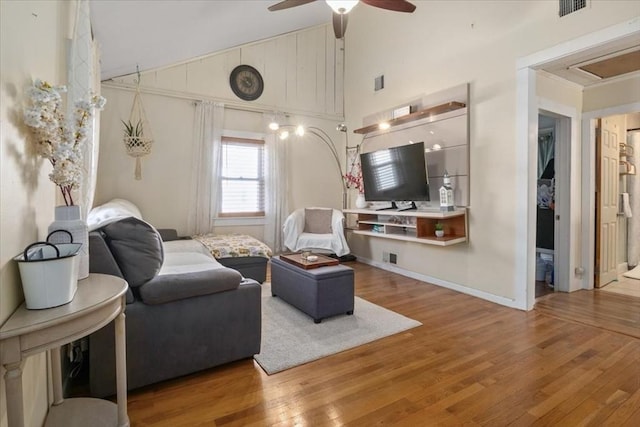 living area with visible vents, baseboards, wood finished floors, high vaulted ceiling, and a ceiling fan