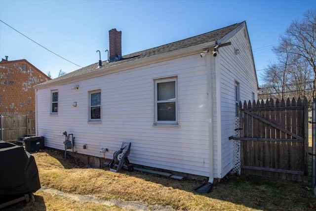 view of side of home featuring fence and a chimney