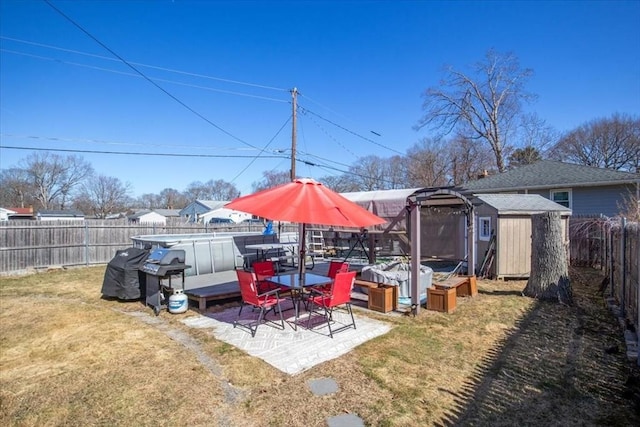 view of yard featuring an outbuilding, a fenced backyard, a shed, a pool, and a patio area