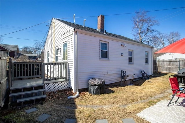 rear view of house with a wooden deck, a chimney, and fence