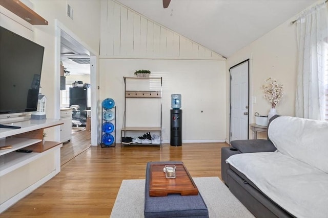 living room with light wood finished floors, visible vents, a ceiling fan, and lofted ceiling