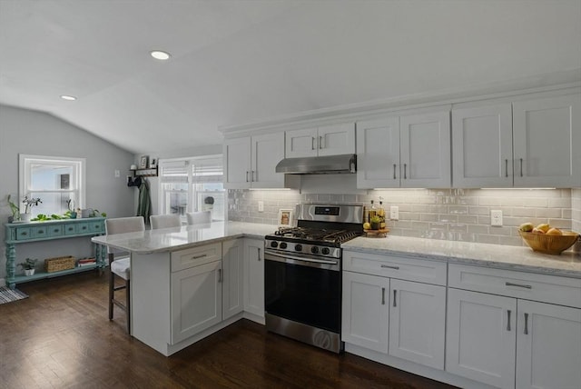 13 Kingston St, North Reading, MA 01864 - kitchen featuring stainless steel range with gas cooktop, lofted ceiling, under cabinet range hood, a peninsula, and tasteful backsplash