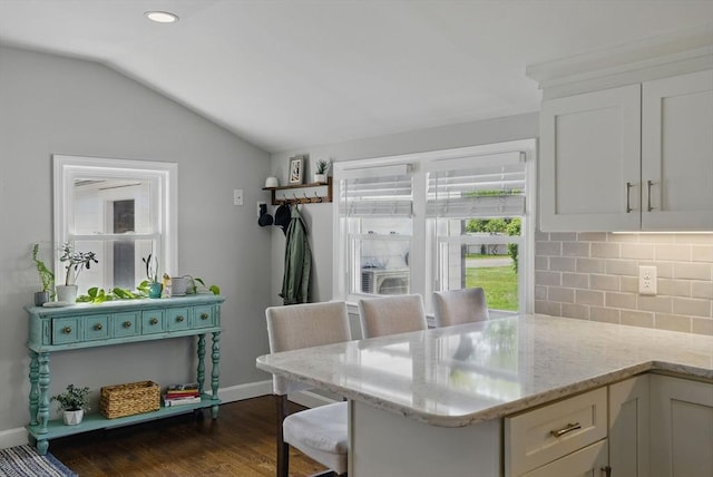 13 Kingston St, North Reading, MA 01864 - kitchen featuring decorative backsplash, white cabinets, dark wood-style flooring, vaulted ceiling, and light stone counters