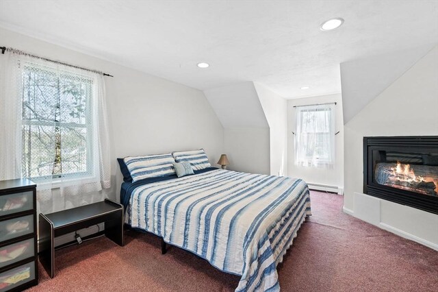 carpeted bedroom with recessed lighting, a baseboard heating unit, a glass covered fireplace, and vaulted ceiling