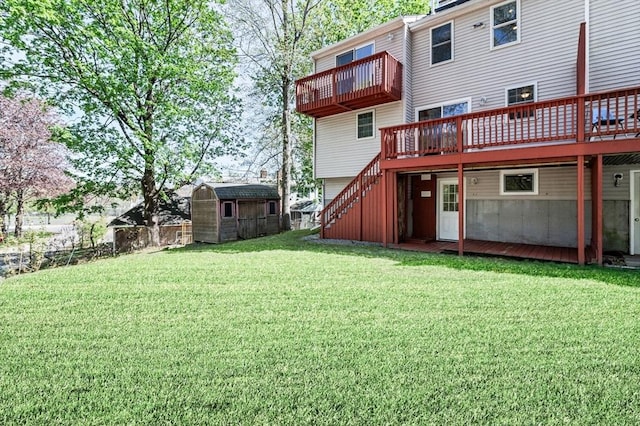 rear view of house featuring an outbuilding, a wooden deck, fence, a storage unit, and a yard