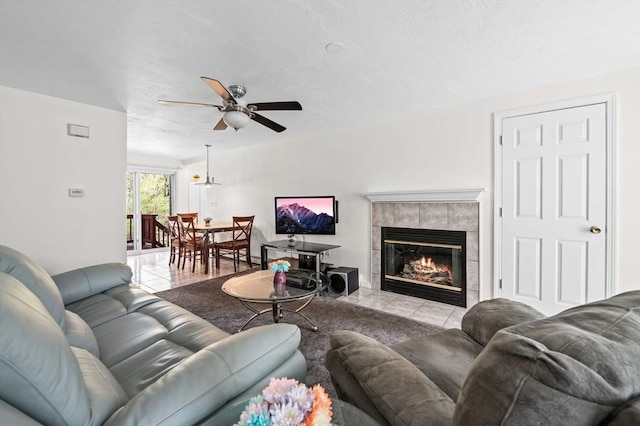 tiled living room with a ceiling fan, a textured ceiling, and a tile fireplace