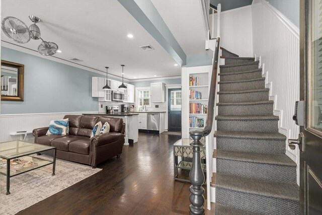 114 Tudor St, Boston, MA 02127 - living area featuring dark wood-style flooring, a wainscoted wall, stairs, ornamental molding, and recessed lighting