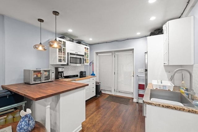114 Tudor St, Boston, MA 02127 - kitchen with butcher block counters, a sink, stainless steel microwave, backsplash, and glass insert cabinets