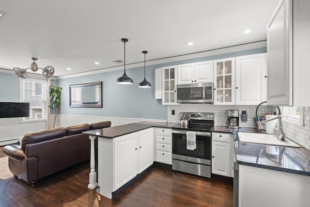 114 Tudor St, Boston, MA 02127 - kitchen with appliances with stainless steel finishes, a sink, a peninsula, white cabinetry, and crown molding